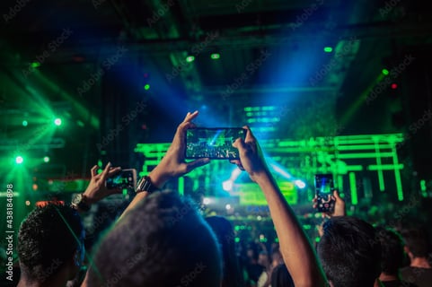 Live concert being captured by audience on smartphones, showcasing user participation in live social media events.