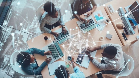 Top view of a diverse team working on laptops with AI in business overlay, symbolizing AI-driven collaboration & innovation.