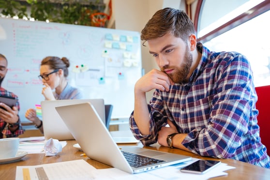 Man with beard intensely looking at his laptop.