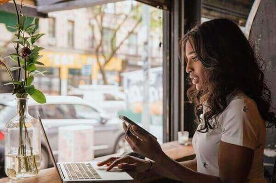 Business owner sitting by a window with her open laptop.