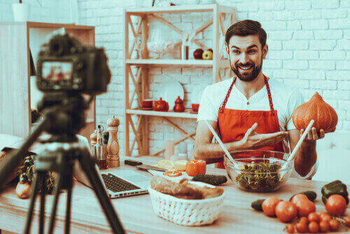 Man in studio interior showing a pumpkin, camera equipment in the foreground.