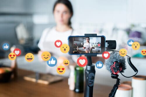 Person livestreaming from kitchen with engagement emojis, representing real-time interaction on live social media.
