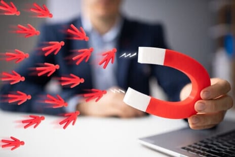 Businessman attracking leads with horseshoe magnet.